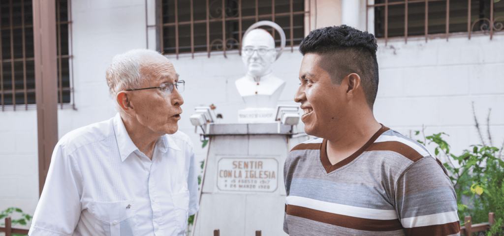 El Padre John Spain conversa con Ronald González Cornejo, participante del grupo juvenil Cristo Salvador, cuya madre y abuela sirvieron en la parroquia con los misioneros Maryknoll. (Octavio Durán/El Salvador)