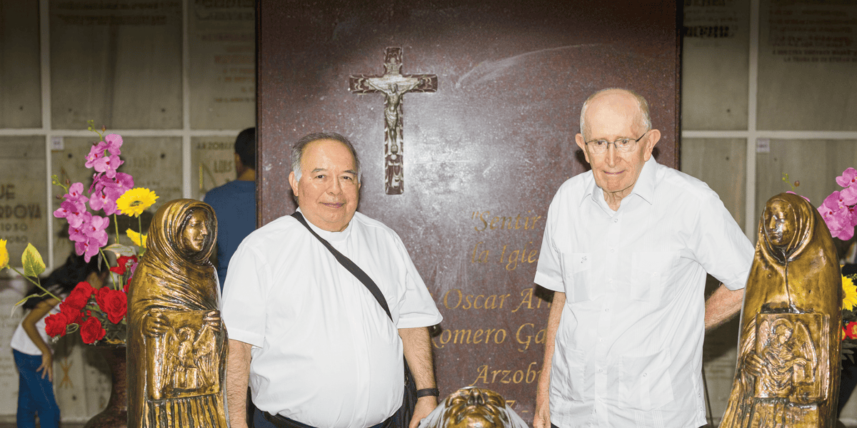 Dos hombres con camisa blanca están entre reliquias religiosas.