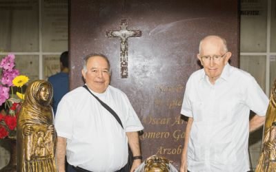 Dos hombres con camisa blanca están entre reliquias religiosas.