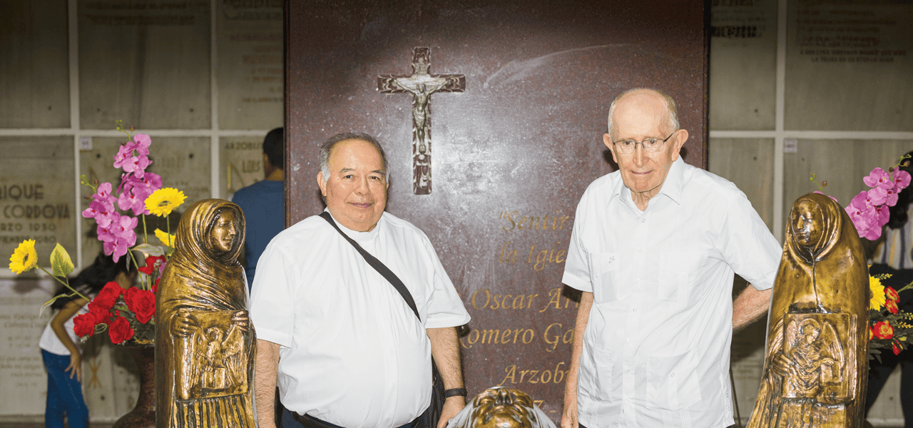 Dos hombres con camisa blanca están entre reliquias religiosas.