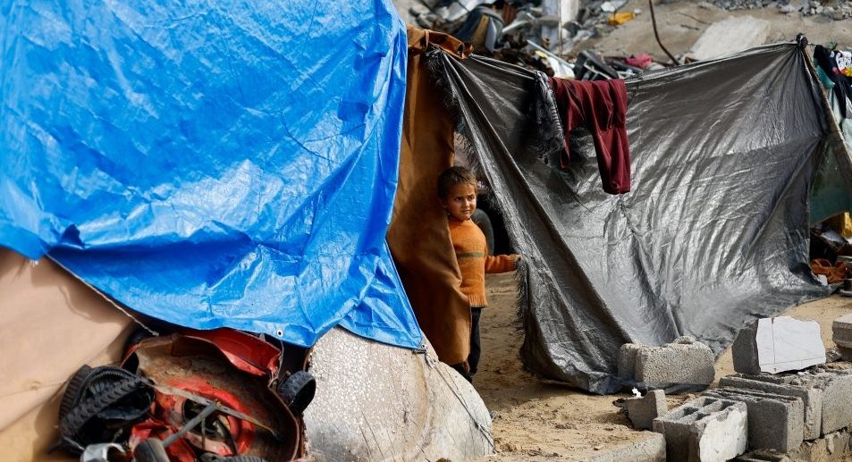 Un niño palestino desplazado observa desde una tienda de campaña cerca de los escombros de edificios residenciales destruidos durante la guerra, en la víspera de Año Nuevo en Jabalia, al norte de la Franja de Gaza, el 31 de diciembre de 2025. El 30 de diciembre, Israel anunció que había suspendido las operaciones de más de dos docenas de organizaciones humanitarias, entre ellas Cáritas. (OSV News/Mahmoud Issa, Reuters)