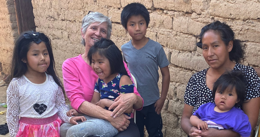 La misionera laica Maryknoll Louise Locke (de camiseta rosa) visita a Lourdes, una madre con cinco niños de los cuales uno sufre de discapacidad, en una comunidad empobrecida en las afueras de Cochabamba, Bolivia. (Cortesía de Louise Locke/Misioneros Laicos Maryknoll/Bolivia)