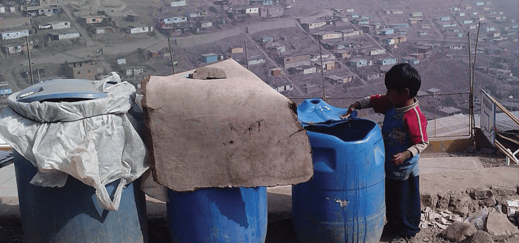 Un niño busca agua de contenedores en Lima, Perú, donde el agua es escasa. (Cortesía de SuSanA Secretariat/Wikimedia Commons/Perú)