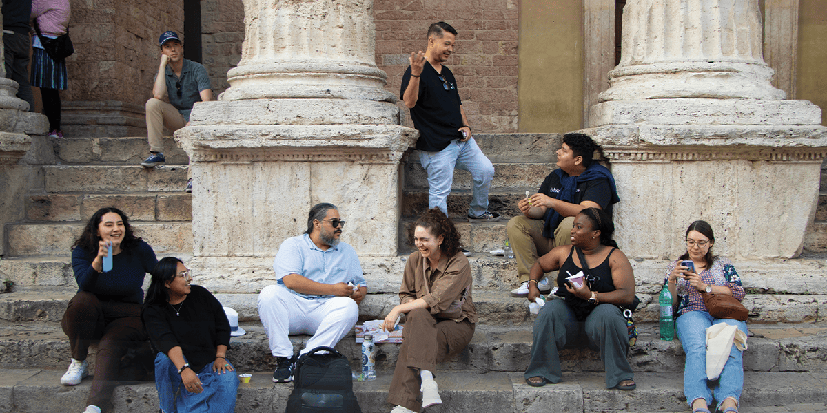 Peregrinos de los Jóvenes Adultos Embajadores Maryknoll y Jóvenes Adultos del Catholic Climate Covenant conversan frente a una iglesia en Asís. (Andrea Moreno-Díaz/Italia)