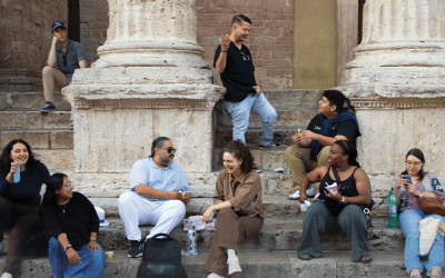 Peregrinos de los Jóvenes Adultos Embajadores Maryknoll y Jóvenes Adultos del Catholic Climate Covenant conversan frente a una iglesia en Asís. (Andrea Moreno-Díaz/Italia)