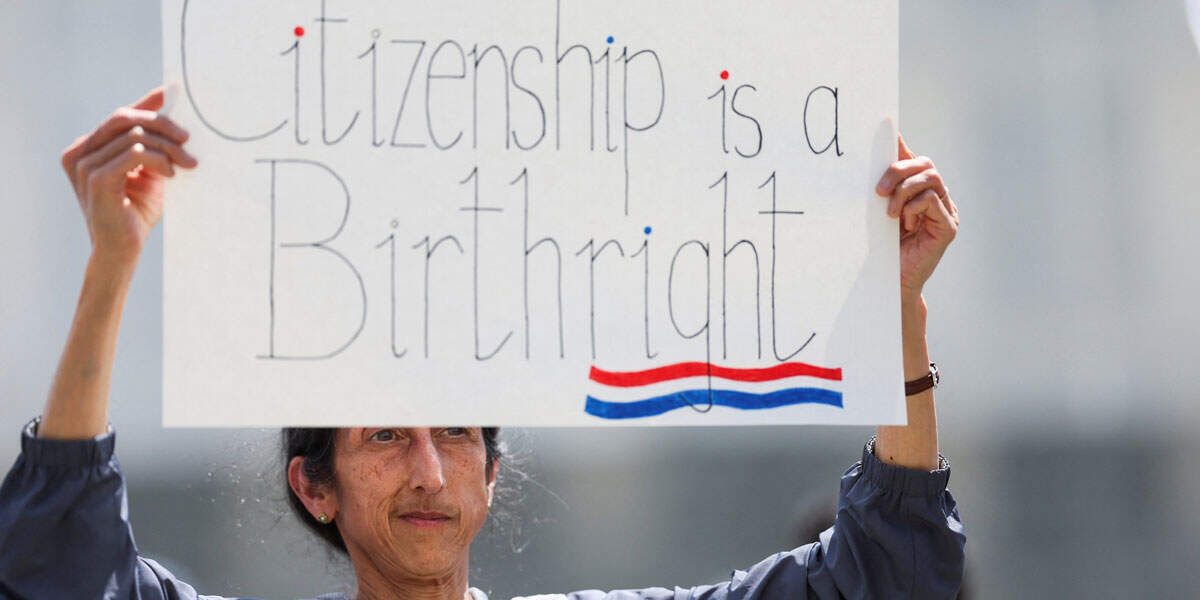Un manifestante sostiene una pancarta durante una protesta frente a la Suprema Corte el 15 de mayo de 2025, mientras los jueces escuchaban los argumentos orales en el caso Trump contra CASA, relacionado con la orden judicial de los tribunales inferiores que suspendía la orden ejecutiva de Trump del 20 de enero de 2025 para poner fin a la ciudadanía por nacimiento. En una decisión de 6 a 3, la Suprema Corte limitó el 27 de junio el alcance de los tribunales federales para bloquear las políticas presidenciales en todo el país. El 1 de abril de 2026, el tribunal escuchará los argumentos orales en el caso Trump contra Barbara, una impugnación de la orden que pone fin a la ciudadanía por nacimiento. (OSV News/Leah Millis, Reuters)