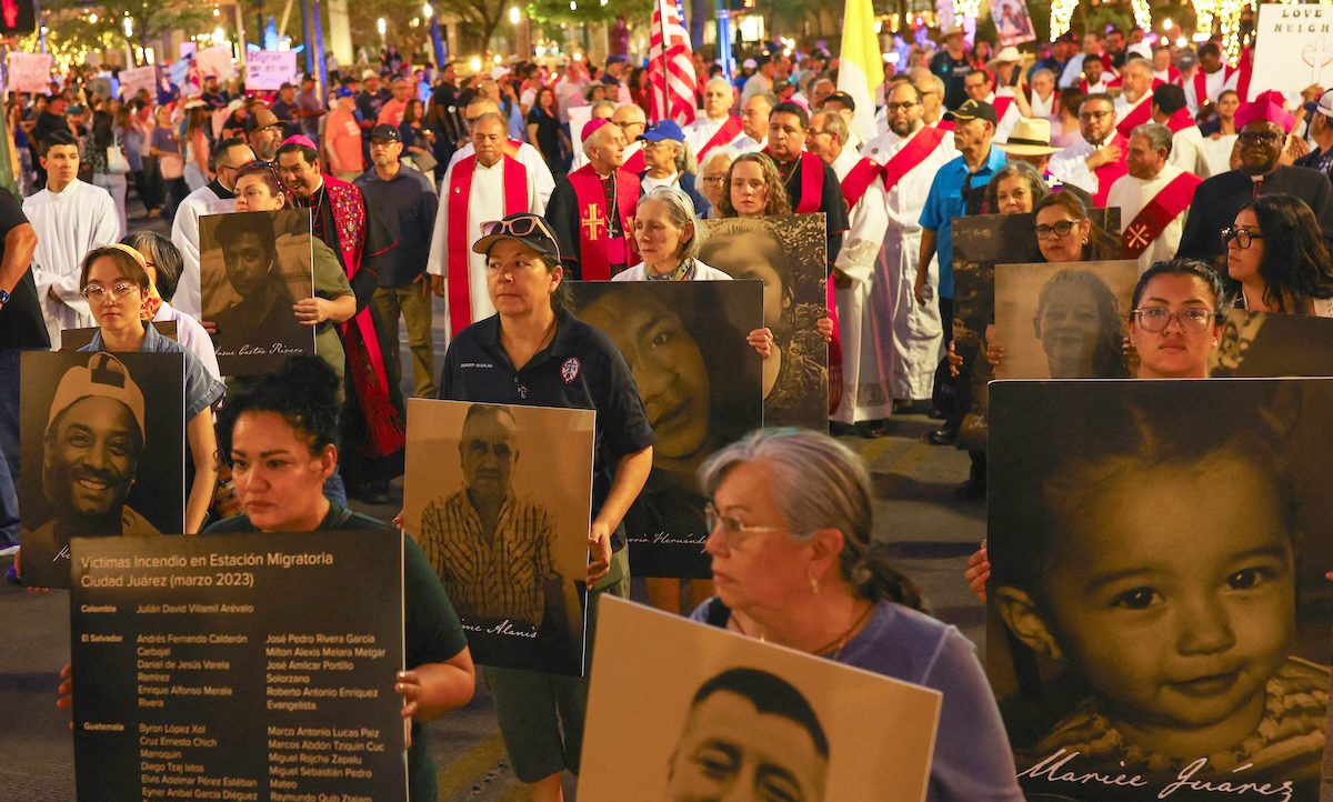 Católicos y otros manifestantes sostienen pancartas con fotografías y nombres de personas que fallecieron en circunstancias relacionadas con la migración, mientras participan en una protesta en El Paso, Texas, el 24 de marzo de 2026, en contra de las deportaciones masivas y las políticas migratorias de la administración Trump. Se puede ver al obispo Mark J. Seitz de El Paso –situado al centro y portando un solideo episcopal– participando en la protesta. (Foto OSV News/José Luis González)