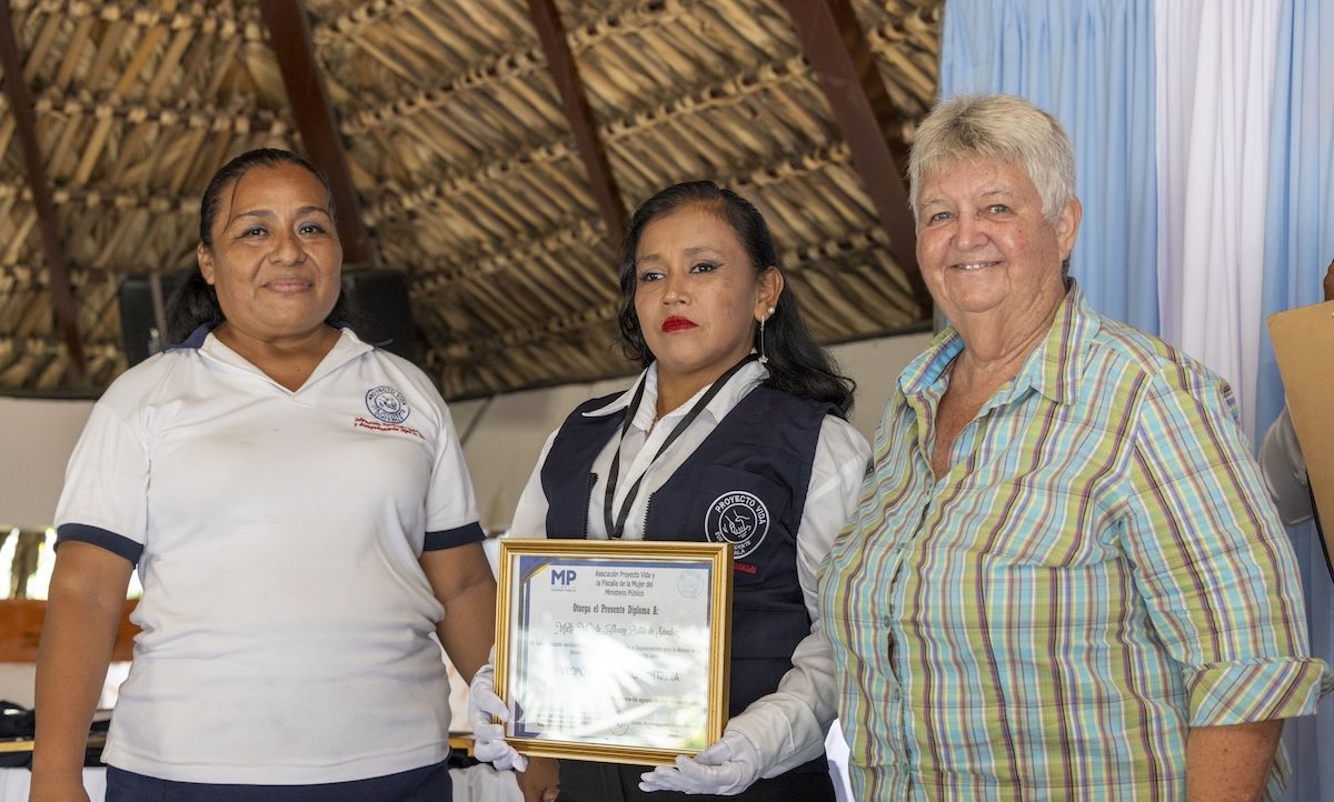 Luz Elizabeth «Lux» Hernández (izq.) y la Hermana Maryknoll Delia «Dee» Smith (dcha.) formalmente incorporan a una candidata como promotora legal comunitaria, otorgándole un chaleco, identificación y diploma. El programa liderado por Lux y la Hermana Maryknoll Dee culminó en una ceremonia de graduación para 18 participantes el 15 de agosto del 2024, en el pueblo de Pajapita en el departamento de San Marcos, Guatemala. (Octavio Durán/Guatemala).