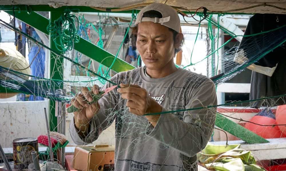 Un pescador migrante repara una red de pesca en el puerto de Taichung, el segundo más grande de Taiwán. Mucho del personal que trabaja en botes de pesca son inmigrantes de las Filipinas y otras naciones asiáticas. (Paul Jeffrey/Taiwán)
