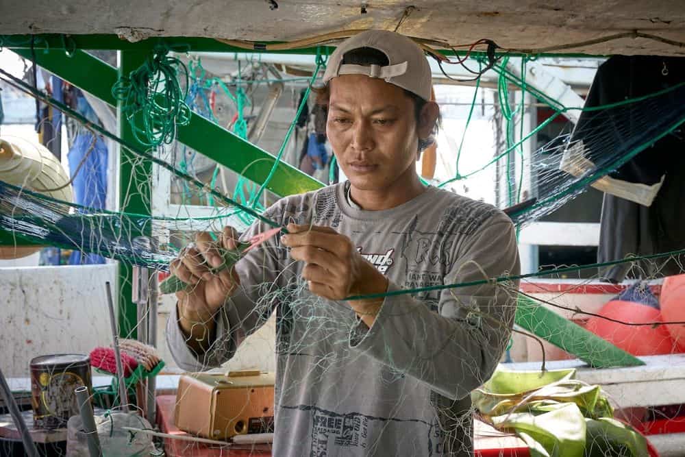 Un pescador migrante repara una red de pesca en el puerto de Taichung, el segundo más grande de Taiwán. Mucho del personal que trabaja en botes de pesca son inmigrantes de las Filipinas y otras naciones asiáticas. (Paul Jeffrey/Taiwán)