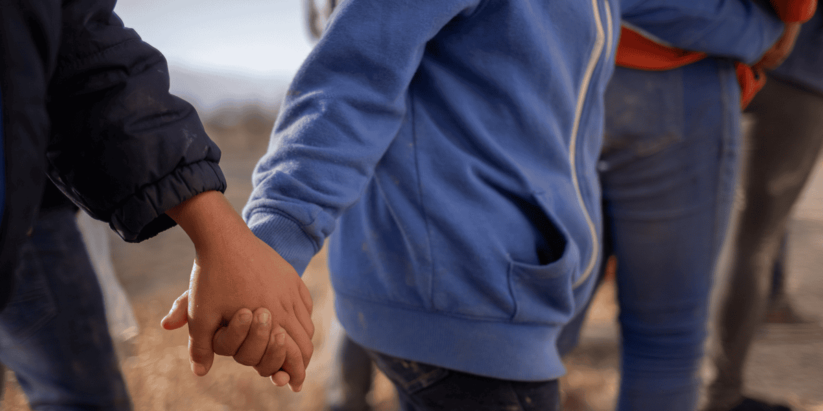Menores no acompañados procedentes de Centroamérica que buscan asilo en Estados Unidos se toman de las manos mientras esperan transporte en Penitas, Texas, el 12 de marzo de 2021, tras cruzar el Río Grande. (Foto de CNS/Adrees Latif, Reuters)