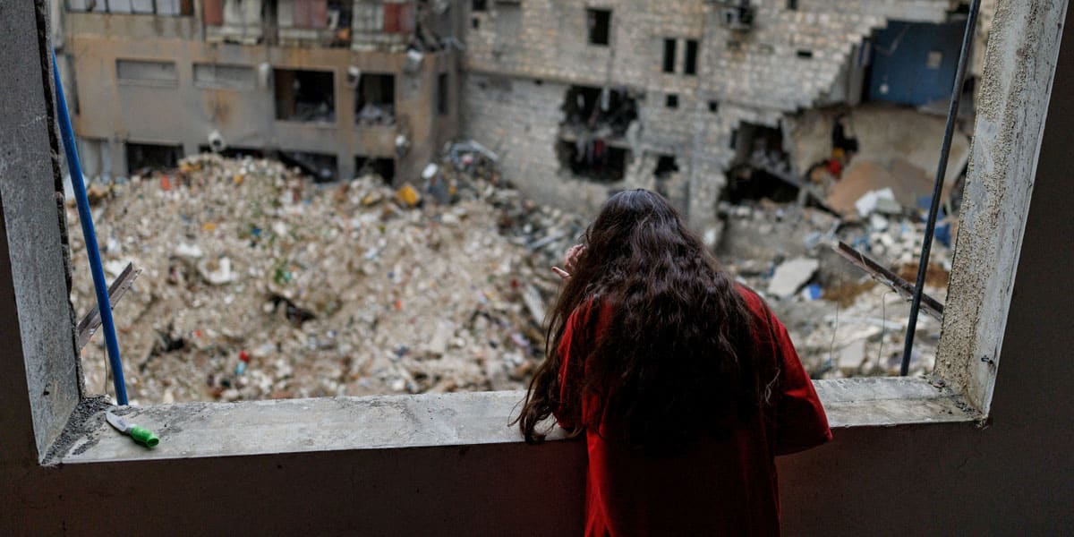 Alaa Dahnoun, de 12 años, quien dijo que sobrevivió a un ataque israelí que la obligó a huir con sus padres a Beirut, mira a través de la ventana dañada de su apartamento en Nabatieh, Líbano, el 18 de abril de 2026, después de que entrara en vigor un alto el fuego de 10 días entre Líbano e Israel. (Foto OSV News/Zohra Bensemra, Reuters)
