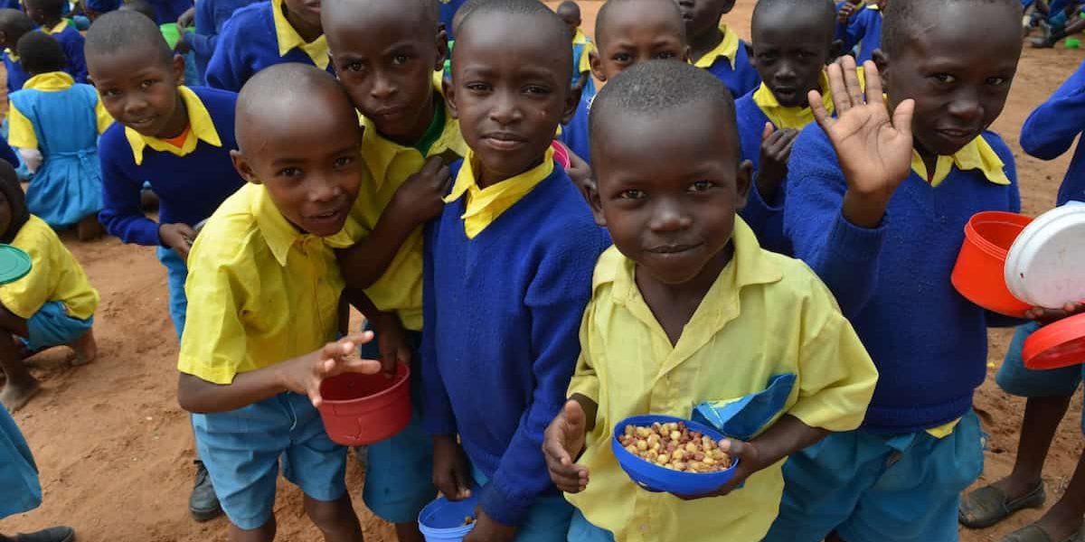 Estudiantes disfrutan una comida saludable el la escuela primara King’utheni en la área afectada por la sequía en Kibwezi, al sur de Kenia, donde misioneros Maryknoll patrocinan varios proyectos.(Moses Njagua Gitahi/Kenya)