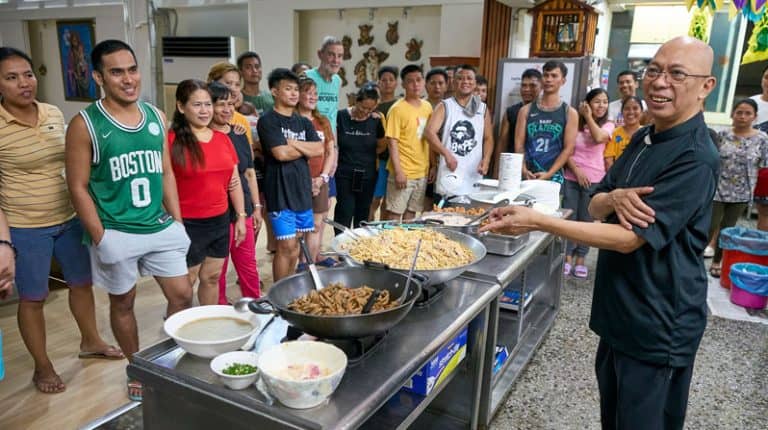 El Padre Maryknoll Joyalito Tajonera, (a la derecha), saluda a los acogidos durante una comida en el albergue Ugnayan, situado en la iglesia católica de Tanzi. El albergue acoge a un promedio de 30 residentes, pero el Padre Tajonera afirma que nunca se rechaza a nadie. (Paul Jeffrey/Taiwán)