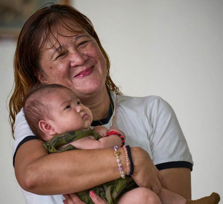 Marivic Arévalo, una trabajadora migrante de Filipinas, sostiene en brazos al bebé de otra mujer. Las trabajadoras migrantes embarazadas, que a menudo se quedan sin hogar cuando pierden su empleo, encuentran refugio en el albergue de acogida, donde se les atiende a ellas y a sus hijos. (Paul Jeffrey/Taiwán)