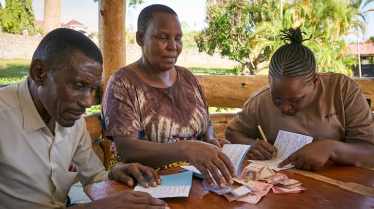 Emmanuel Timoth (izquierda), Rhobi Mgole y Carorina Paschal llevan un registro de sus ahorros. Ellos participan en un grupo de ahorro gestionado por el Centro Uzima, una organización comunitaria patrocinada por Maryknoll que apoya y empodera a las personas con VIH. (Paul Jeffrey/Tanzania)
