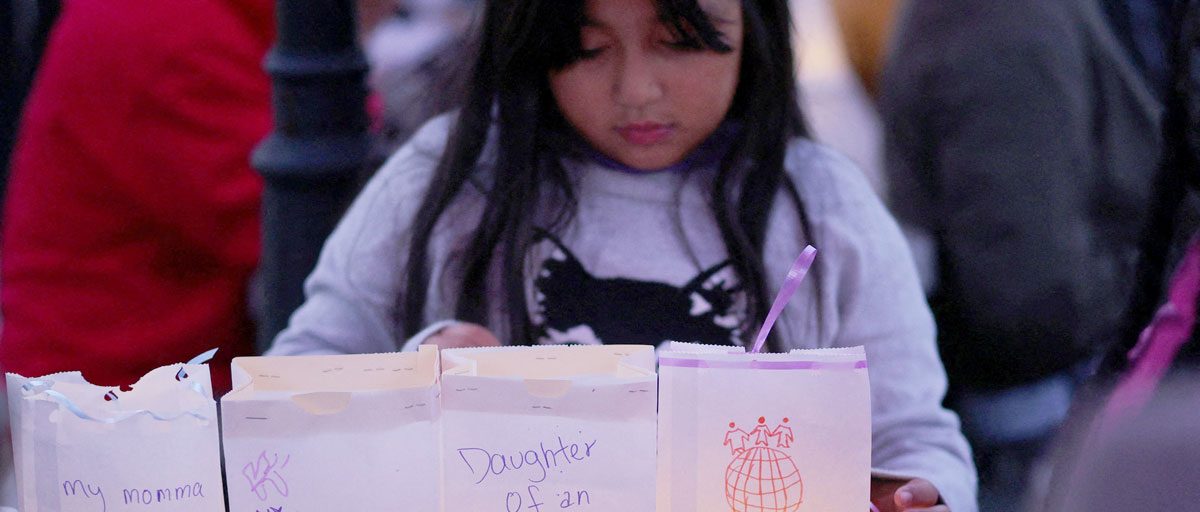 Zuanny, de ocho años, coloca luminarias con mensajes de su madre —una “Dreamer” del programa DACA—, de ella misma y de sus hermanas, durante una vigilia en La Colaborativa, en Chelsea, Massachusetts, en 2025, en apoyo a la comunidad afectada por las redadas y detenciones realizadas por el Servicio de Inmigración y Control de Aduanas. (OSV News / Brian Snyder, Reuters)