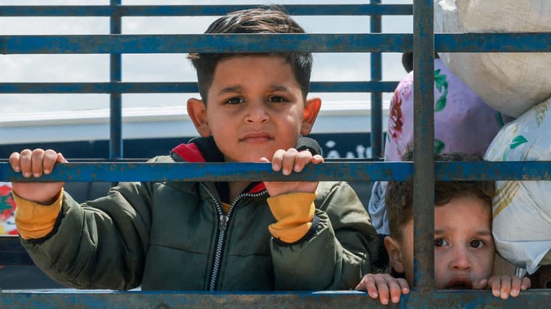 Niños desplazados observan el entorno mientras viajan en la parte trasera de un camión cargado de pertenencias, rumbo a sus hogares en el sur del Líbano, en medio de un alto el fuego de 10 días entre el Líbano e Israel; en Qasmiyeh, sur del Líbano, el 20 de abril de 2026. Muchos cristianos en la «tierra de los cedros» ya no creen tener un futuro en la región, declaró el Padre Jan Zelazny, director de la sección polaca de Ayuda a la Iglesia Necesitada, a OSV News el 27 de mayo, durante su viaje al país. (OSV News / Aziz Taher, Reuters)