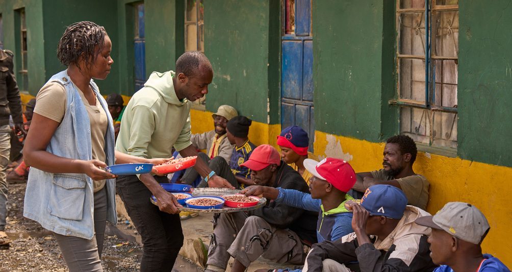 Como parte de su discernimiento al sacerdocio, Babluu Ekama Kyamba sirve comida a familias sin hogar en el barrio de Mathare en Nairobi, Kenia, junto a la voluntaria Elizabeth Omollo. (Paul Jeffrey/Tanzania)