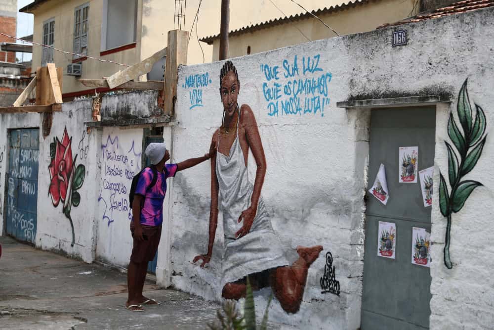 Un hombre observa una obra de arte creada por artistas en homenaje a Kathlen Romeu en un barrio pobre de Río de Janeiro, el 14 de junio de 2021. La diseñadora de interiores, de 24 años, estaba embarazada cuando fue asesinada a tiros el 8 de junio durante una operación policial, según los medios locales. El grafiti dice: “Que tu luz guíe los caminos de nuestra lucha”. (CNS/Pilar Olivares, Reuters)