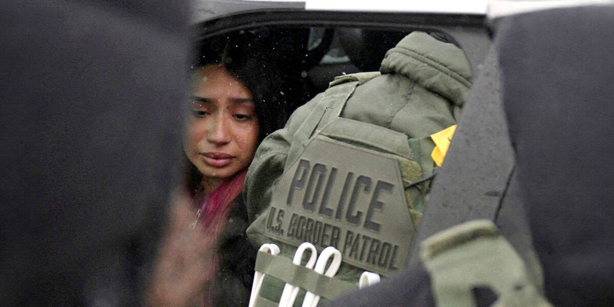 Una mujer detenida se encuentra sentada dentro de un vehículo rodeada de agentes federales en Minneapolis el 21 de enero de 2026. (OSV News/Leah Millis, Reuters)