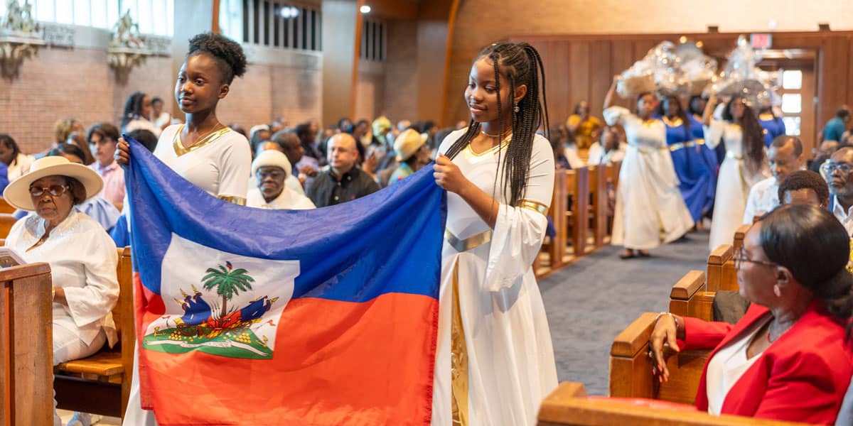 Llevando la bandera de Haití y cestas con frutas y verduras, unas niñas y jóvenes encabezan una procesión de ofrendas durante una Misa celebrada el 28 de junio de 2026 con motivo de la festividad de Nuestra Señora del Perpetuo Socorro, patrona de Haití, en la iglesia de Nuestra Señora de los Dolores de Takoma Park, Maryland. La Misa se celebró para la comunidad católica haitiana de Washington. (OSV News/Mihoko Owada, Catholic Standard)