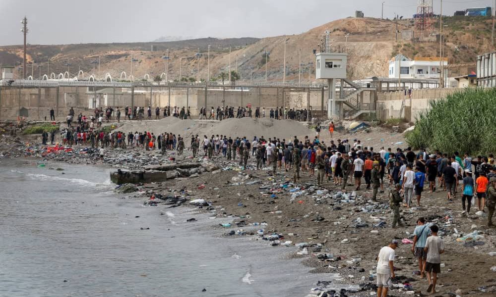 Personas en Ceuta, España, caminan hacia la frontera con Marruecos al abandonar el territorio español el 31 de julio de 2026, en medio de cruces masivos, a pie y por mar, de migrantes desde Marruecos hacia territorio español. La diócesis de Cádiz y Ceuta ofreció recursos de emergencia a las autoridades civiles el 31 de julio, cuando más de 60.000 migrantes cruzaron desde Marruecos al enclave español de Ceuta, lo que saturó la infraestructura local. (OSV News/Jon Nazca, Reuters)