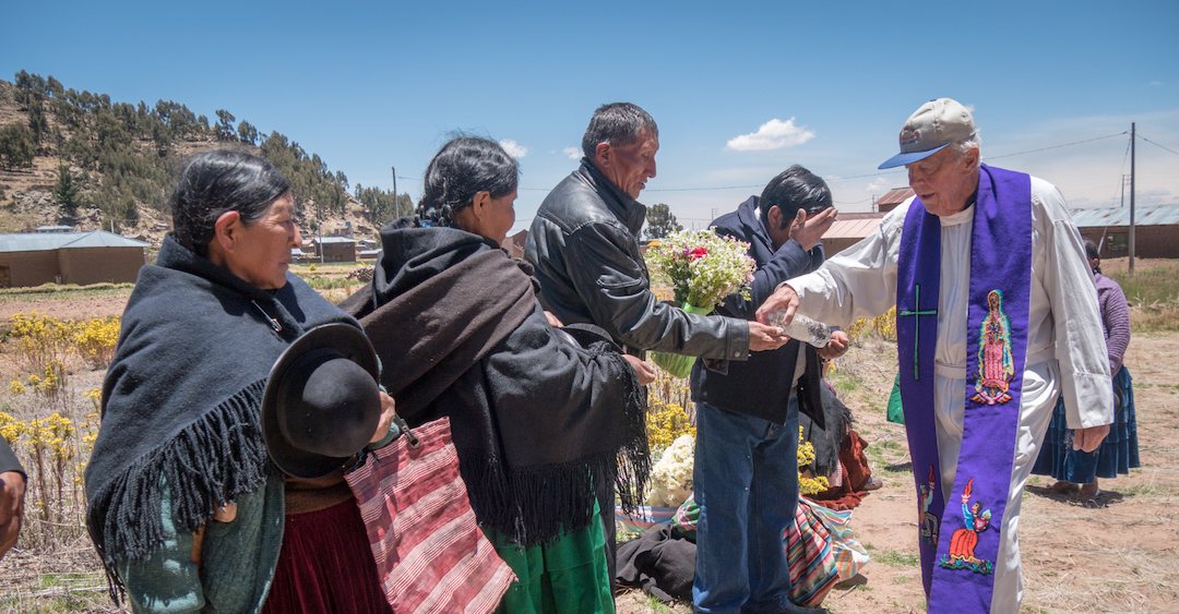 A Maryknoll priest performing service outdoors.