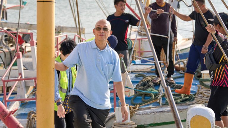 Maryknoll Father Joyalito “Joy” Tajonera stands upon a boat with migrant fisherman in Taiwan.