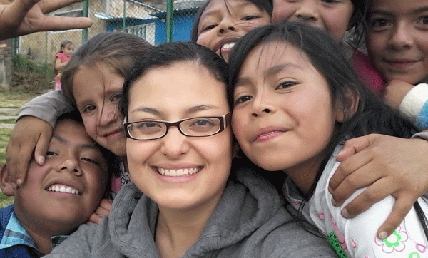 A woman being hugged by seven children.
